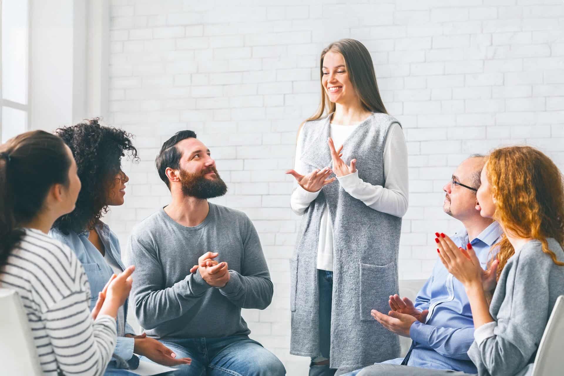 Happy Woman Sharing Her Recovery Story With Group On Therapy Session
